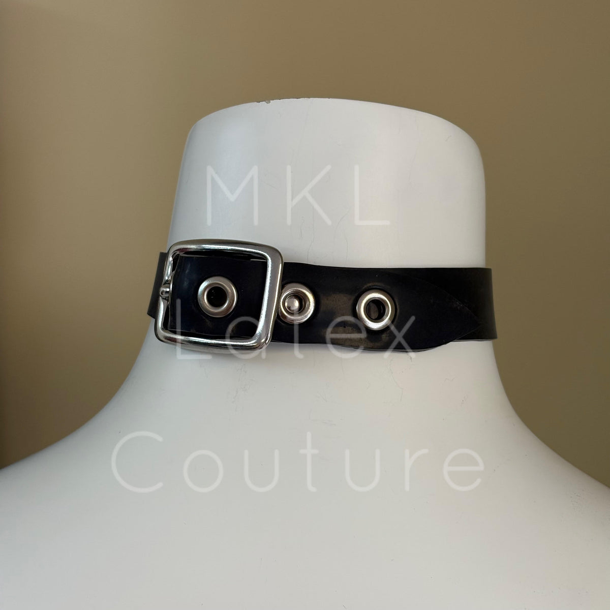Heavy latex choker with a central metal heart shape secured in place by studs with a back buckles with 4 eyelets for adjustment.